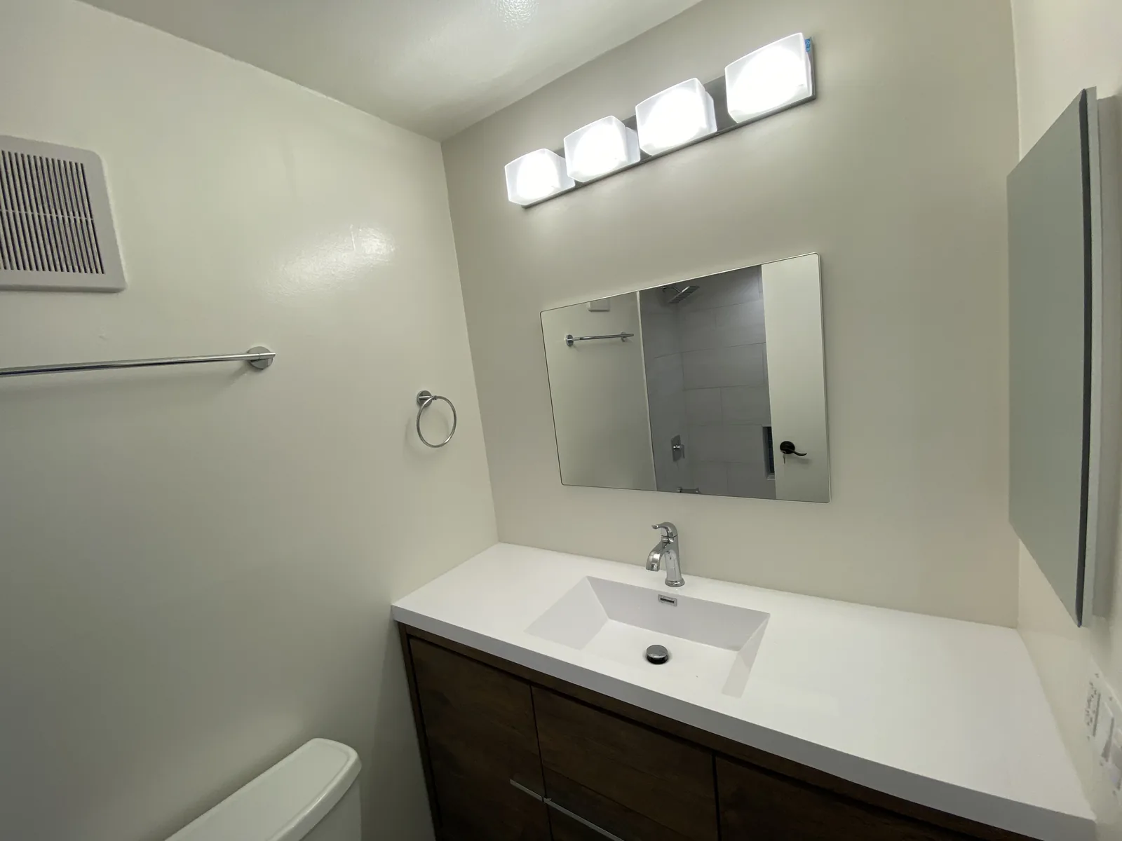 The finished second bathroom with a dark wood vanity and white countertop