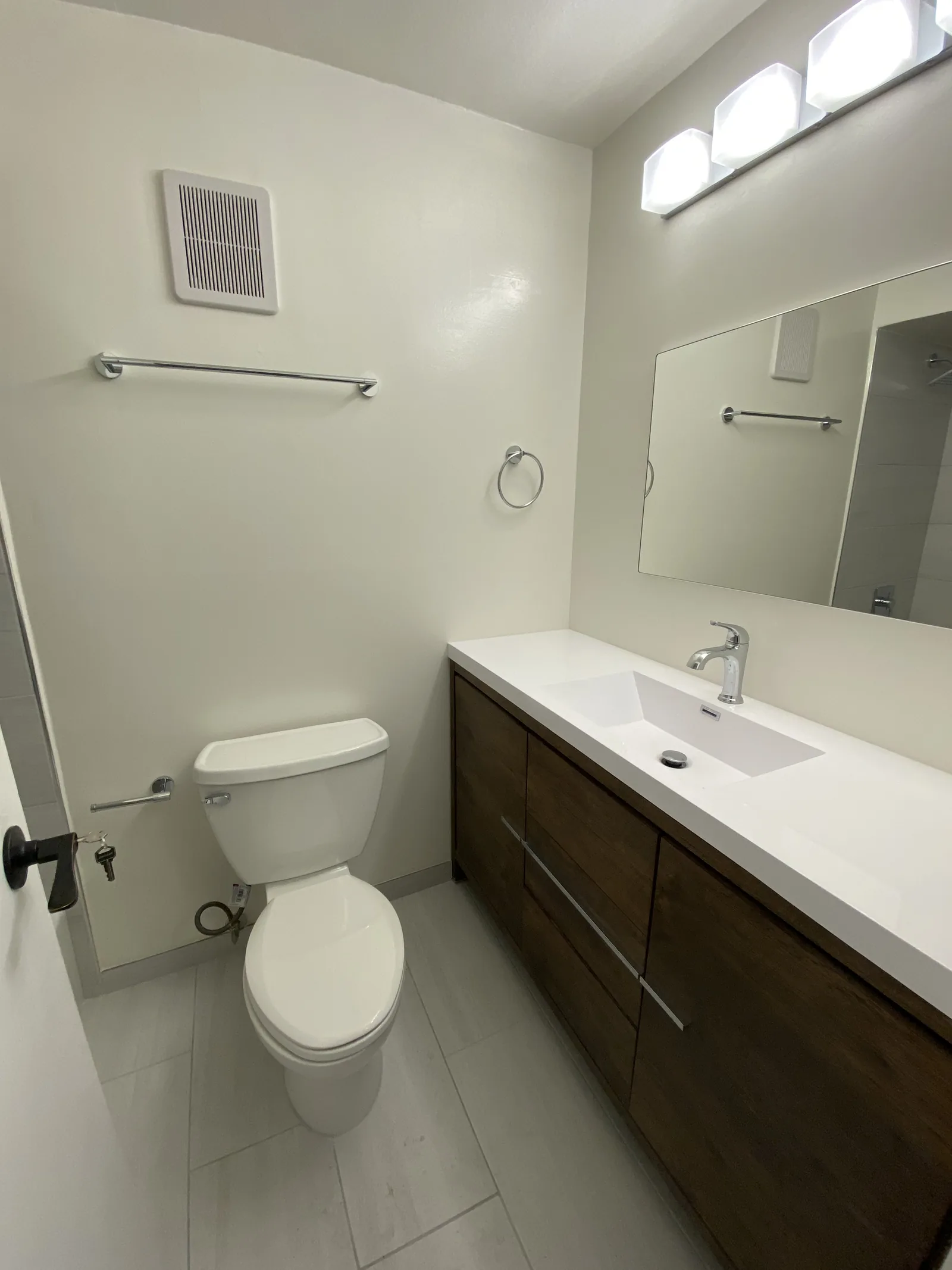 The finished second bathroom with the toilet, tile floor, and walk-in shower