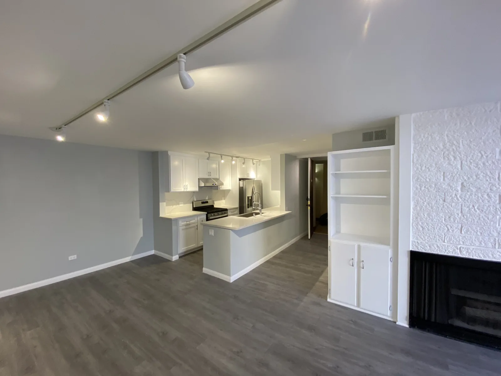 The finished kitchen opening onto the living room with the fireplace and built-ins visible beyond