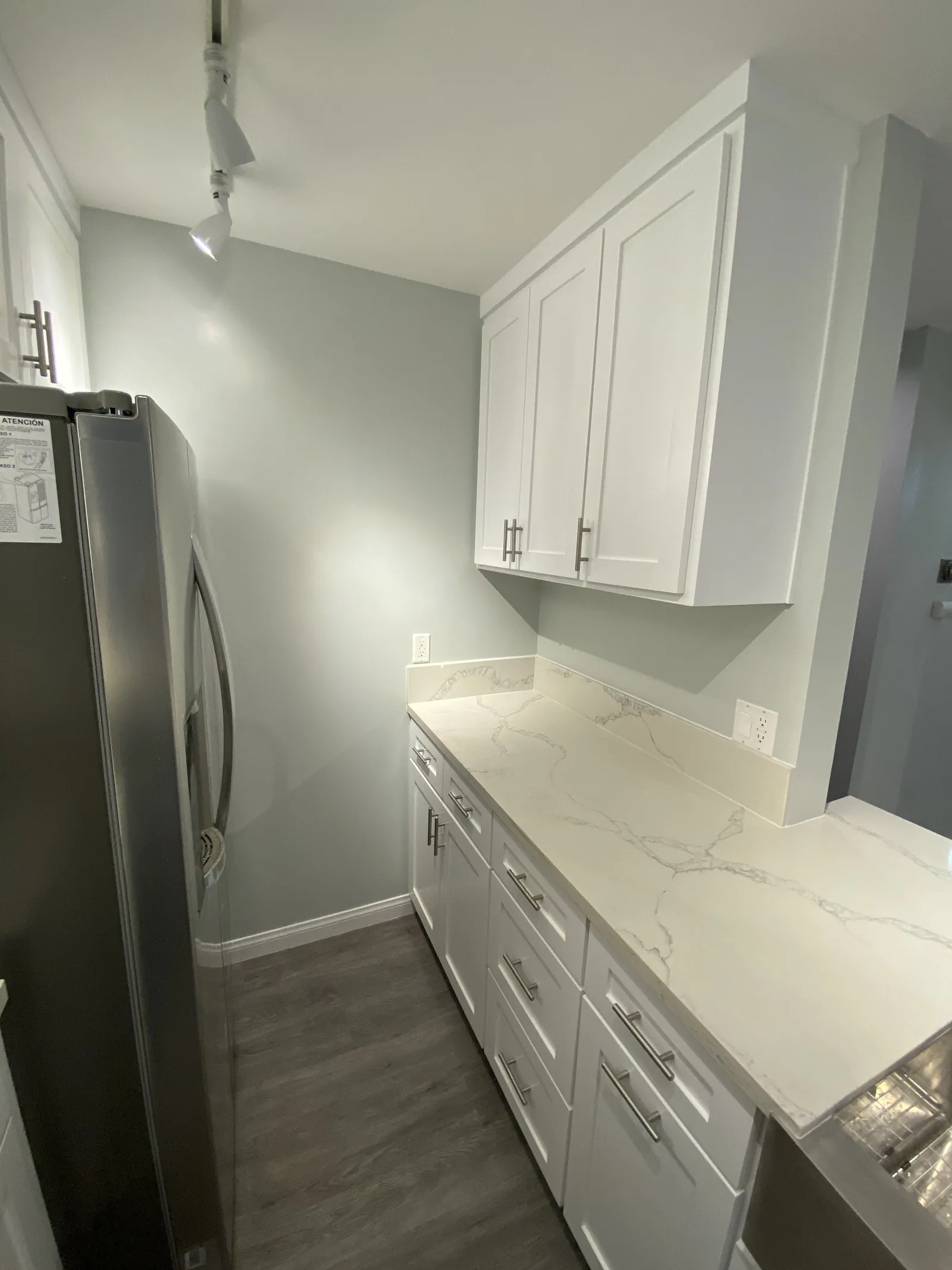 The finished kitchen with the refrigerator and counter, hallway visible beyond