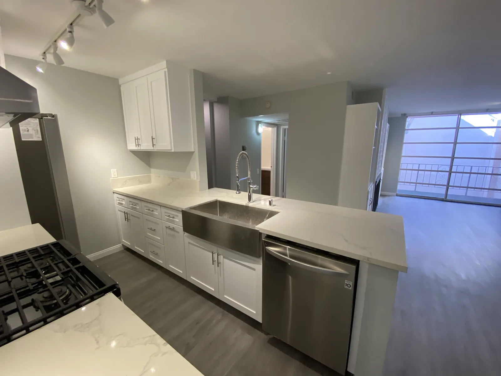 The finished kitchen peninsula with a farmhouse sink and dishwasher, opening onto the living area